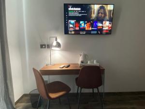 a desk with two chairs and a monitor on the wall at Holiday Guesthouse in Salerno