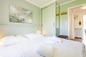 een slaapkamer met een wit bed en een schilderij aan de muur bij Haus Friesische Strasse 25a Whg 1 in Westerland