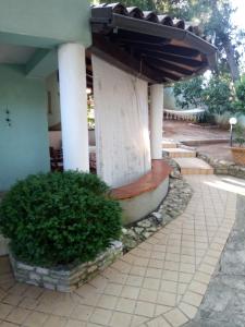 a building with a porch with a bush in front of it at Villa Verde Apartments and Rooms in Premantura