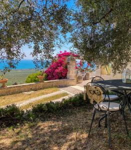 einen Tisch und Stühle unter einem Baum mit Blumen in der Unterkunft Villa Basso 2 in Monte SantʼAngelo