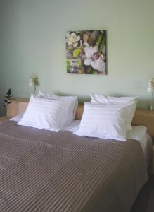 a bed with white pillows and a painting on the wall at Nette in Pärnu