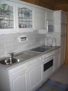 una cucina con armadi bianchi e lavandino di Appartement Sonnberg a Forstau