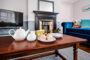 a living room with a coffee table with tea pots and cupcakes at The Grange, Aldeburgh in Aldeburgh