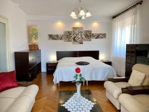 Un dormitorio con una cama y una mesa con un jarrón con una flor roja en Apartments Villa Mattossi, en Rovinj