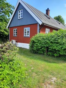 a red house with a blue roof and a yard at Smultronbacken in Eljaröd