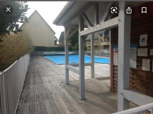 a swimming pool with a pavilion next to a wooden deck at F3 proche Deauville Piscine in Touques