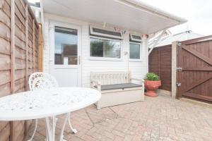 a patio with a table and a white table and a fence at Mayberry Lodge in Selsey