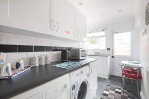 a white kitchen with a washing machine in it at Mayberry Lodge in Selsey