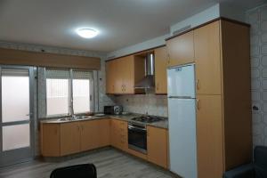 kuchnia z drewnianymi szafkami i białą lodówką w obiekcie CASA DA MADRIÑA w mieście Cambados