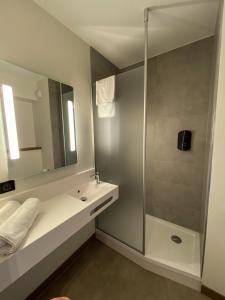 a bathroom with a shower and a sink and a mirror at B&B HOTEL Clermont-Ferrand A71-A75 La Méridienne in Clermont-Ferrand