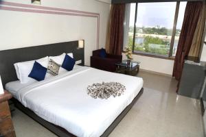 um quarto com uma grande cama branca com almofadas azuis em SilverCloud Hotel and Banquets em Ahmedabad