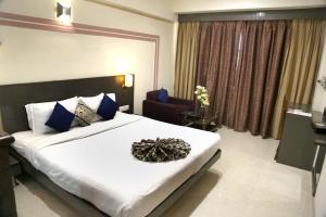 1 dormitorio con 1 cama blanca grande y 1 silla en SilverCloud Hotel and Banquets, en Ahmedabad