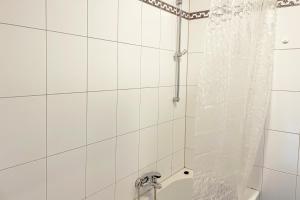 a white tiled shower with a shower curtain in a bathroom at Schöne 3 Zimmerwohnung in Düren in Düren - Eifel