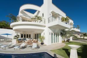 a white house with a swimming pool in front of it at Exquisite Hilltop Villa with Luxurious Modern Design, Sweeping Ocean Views & Sparkling Infinity Pool in Playa Flamingo