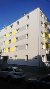duży biały budynek z zaparkowanymi przed nim samochodami w obiekcie Top Sea Apartament 1 w Gdańsku