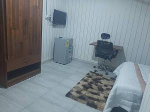 1 dormitorio con cama, escritorio y silla en MAXJEN HAVEN GUEST HOUSE, en Kasoa