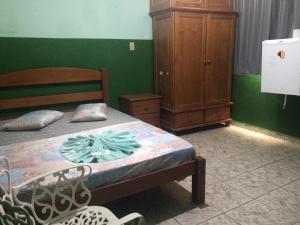 a bedroom with a bed and a wooden cabinet at Hotel Marabá in Jundiaí