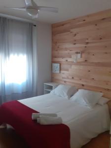 1 dormitorio con 1 cama blanca grande y pared de madera en VIVIENDA LA ESTRELLA, en Tudela