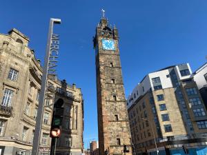 uma torre de relógio alto no meio de uma cidade em Tolbooth Apartments by Principal Apartments em Glasgow