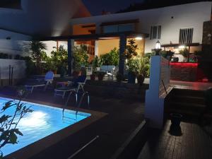 una casa con piscina por la noche en Cactus Guest House en Cidade Velha