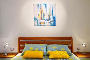 a bed with two yellow pillows and a painting on the wall at Apartman Maksim in Banjole