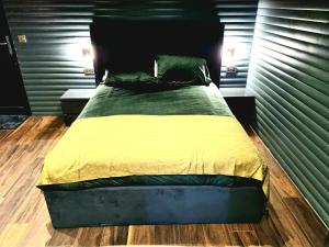 a bed with a green and yellow comforter in a bedroom at Yaseva Lodge, Stylish Country Retreat for 2, Hot Tub, Exceptional Views! in Carr