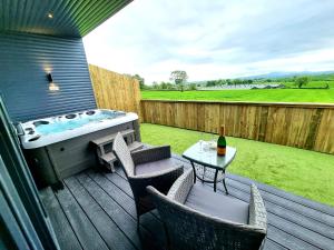 una terraza con bañera de hidromasaje y una mesa con sillas en Yaseva Lodge, Stylish Country Retreat for 2, Hot Tub, Exceptional Views!, en Carr