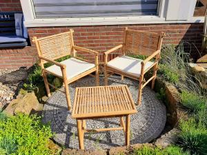 2 chaises en bois et un banc assis à côté d'un bâtiment dans l'établissement WadLeuk!, à Le Helder