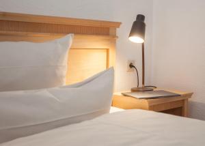 a bed with a white pillow and a lamp on a table at Der schöne Asten - Resort Winterberg in Winterberg