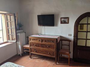 una camera da letto con cassettiera e televisione sul muro di The Roof House in Piazza Grande Montepulciano vista Duomo e centro storico a Montepulciano