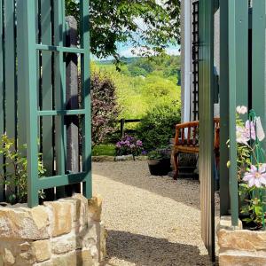 a door to a garden with a bench and flowers at Elm Tree Cottage in Fivemiletown