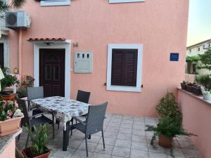 une table et des chaises devant un bâtiment rose dans l'établissement Apartment Sofia, à Mali Lošinj