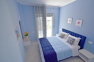 a blue bedroom with a bed and a window at SunRise Suites in Vlorë