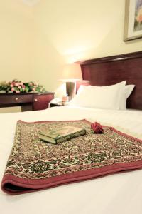 a bed with a blanket with a book on it at فندق غالية احد in Al Madinah