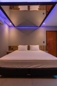 a bedroom with a large white bed with blue lights at Drops Motel São José do Rio Preto in Sao Jose do Rio Preto