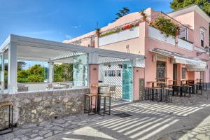 a restaurant with tables and chairs outside of a pink building at Boutique Hotel Casa Mariantonia in Anacapri