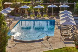 アナカプリにあるブティック ホテル カサ マリアントニアのパラソルと椅子付きのスイミングプール、プールを提供しています。