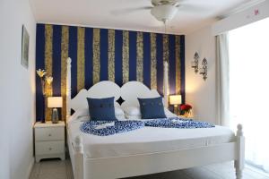 een slaapkamer met een groot wit bed met blauwe kussens bij Villa Boscardi in Belize City