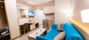 a living room with a blue couch and a kitchen at Riviera Olympus Gods in Paralia Katerinis
