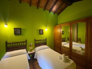zieloną sypialnię z 2 łóżkami i lustrem w obiekcie La Helguera Vivienda Vacacional w mieście Villanueva