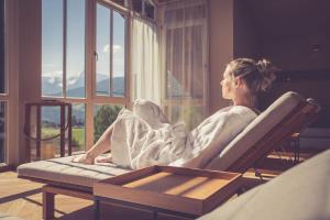 a woman sitting in a chair looking out the window at Hotel Annelies in Ramsau am Dachstein