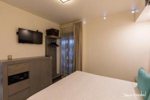 1 dormitorio con 1 cama y TV en la pared en Marialicia Suites, Hotel Boutique en Oaxaca de Juárez