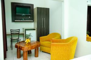 un soggiorno con un divano giallo e un tavolo di Hotel Della Vita a Glória de Dourados