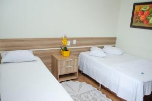 una camera con due letti e un vaso di fiori di Hotel Della Vita a Glória de Dourados