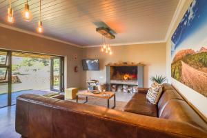 a living room with a brown leather couch and a fireplace at Steenbok farm cottages Aalwyn Cottage in Wolseley