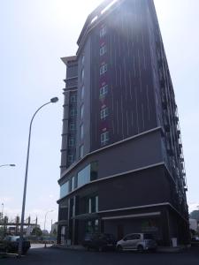 ein hohes schwarzes Gebäude mit Autos auf einem Parkplatz in der Unterkunft MidCity Hotel Melaka in Malakka