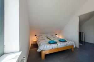 a bedroom with a bed with blue pillows on it at Huize Kreek en Zee in Westkapelle