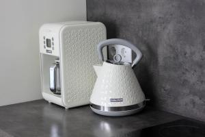 a white tea kettle sitting on a counter next to a microwave at Modern Cozy 1BR apartment in Quiet center of Riga in Rīga
