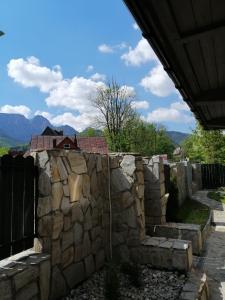 una pared de piedra con una valla y montañas en el fondo en Domek Zakopiańska chata, en Zakopane