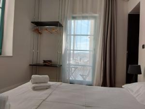 a bedroom with a large white bed with a window at Ermoupolis hidden gems in Ermoupoli